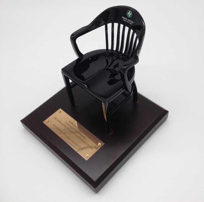 black miniature chair with gold name plate on a brown cherry wood base