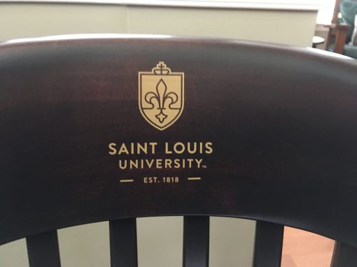 Gold logo of Saint Louis University on brown chair
