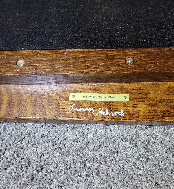 Signature and product nameplate under an oak chair