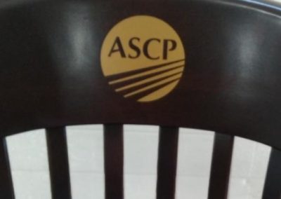 Gold logo of ASCP on dark brown logo chair