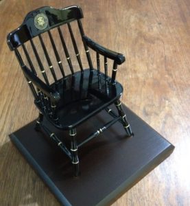One of our black miniature fundraising chairs representing Carnegie Mellon University, on dark brown wooden base