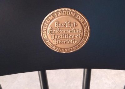 Circular Gold Medallion Dickinson Law on black logo chair - college chairs