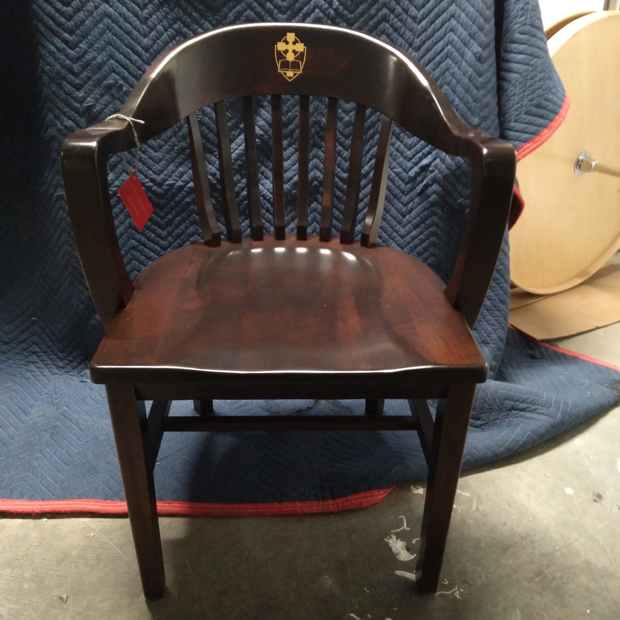 Front view of the Brown Classic Alumni Chair of Church Divinity School of the Pacific with gold "cross" CDSP logo