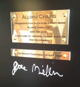 Brass company plate and product plate under a black chair